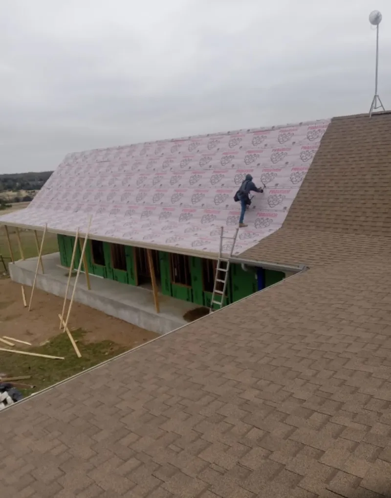 Worker preparing underlayment for a metal roof installation in Eastpointe